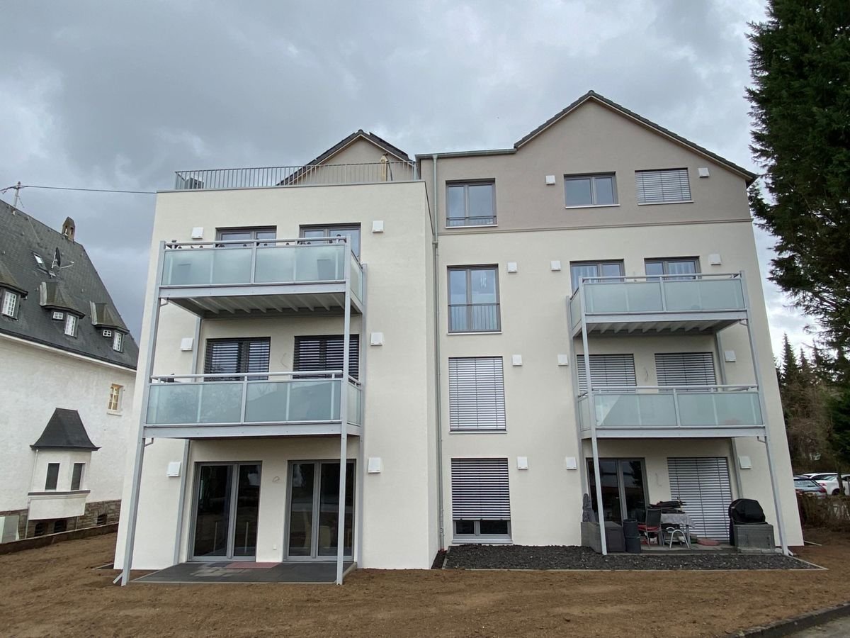 Neu gebautes Mehrfamilienhaus mit hellem Putz, Satteldächern und vorgestellten Balkonen