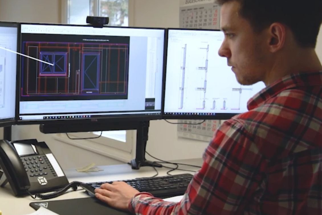 Ein Planer von Holzbau Kappler arbeitet an zwei Bildschirmen mit Wandelementplan und Anschlussdetails.
